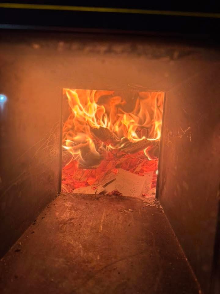 Live flames burning inside the wood-fired sauna stove