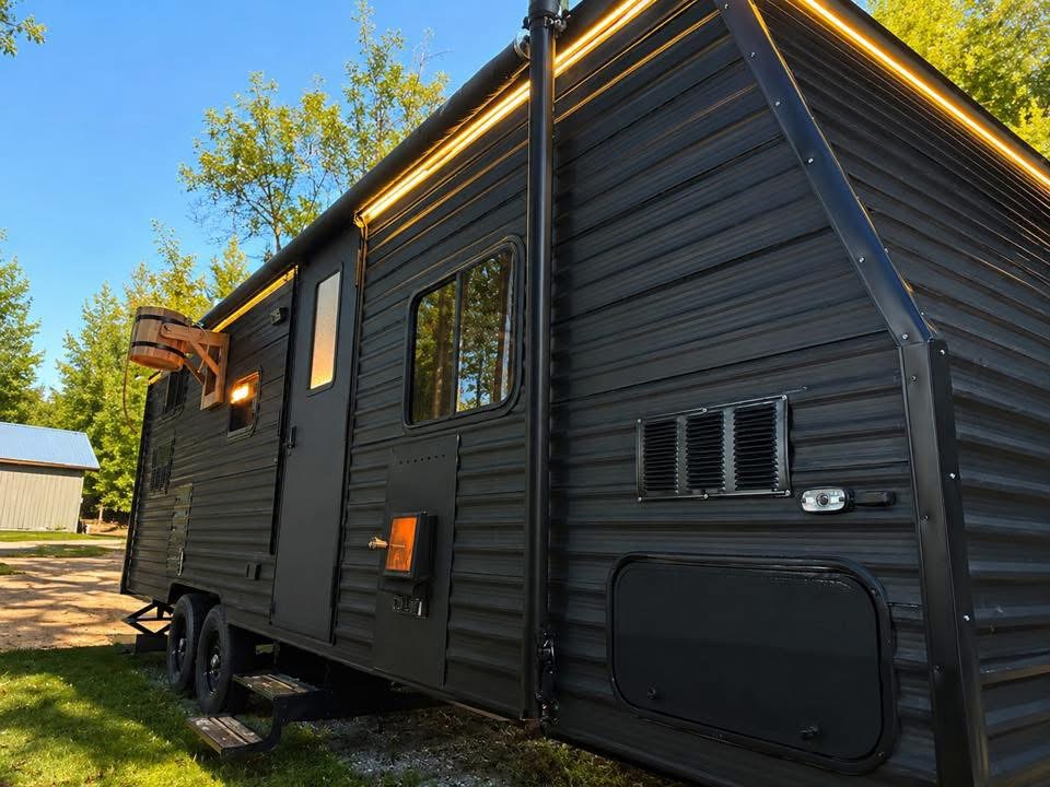 The black Venik Steam mobile sauna trailer parked on grass in evening light