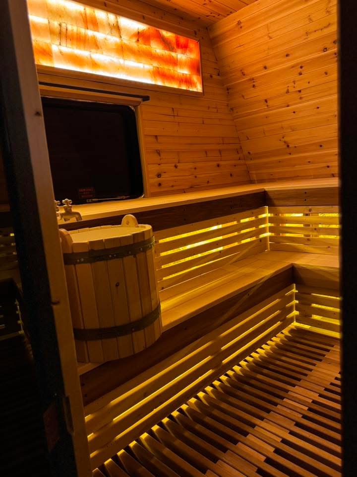 Cedar benches with warm strip lighting and a Himalayan salt panel inside the sauna